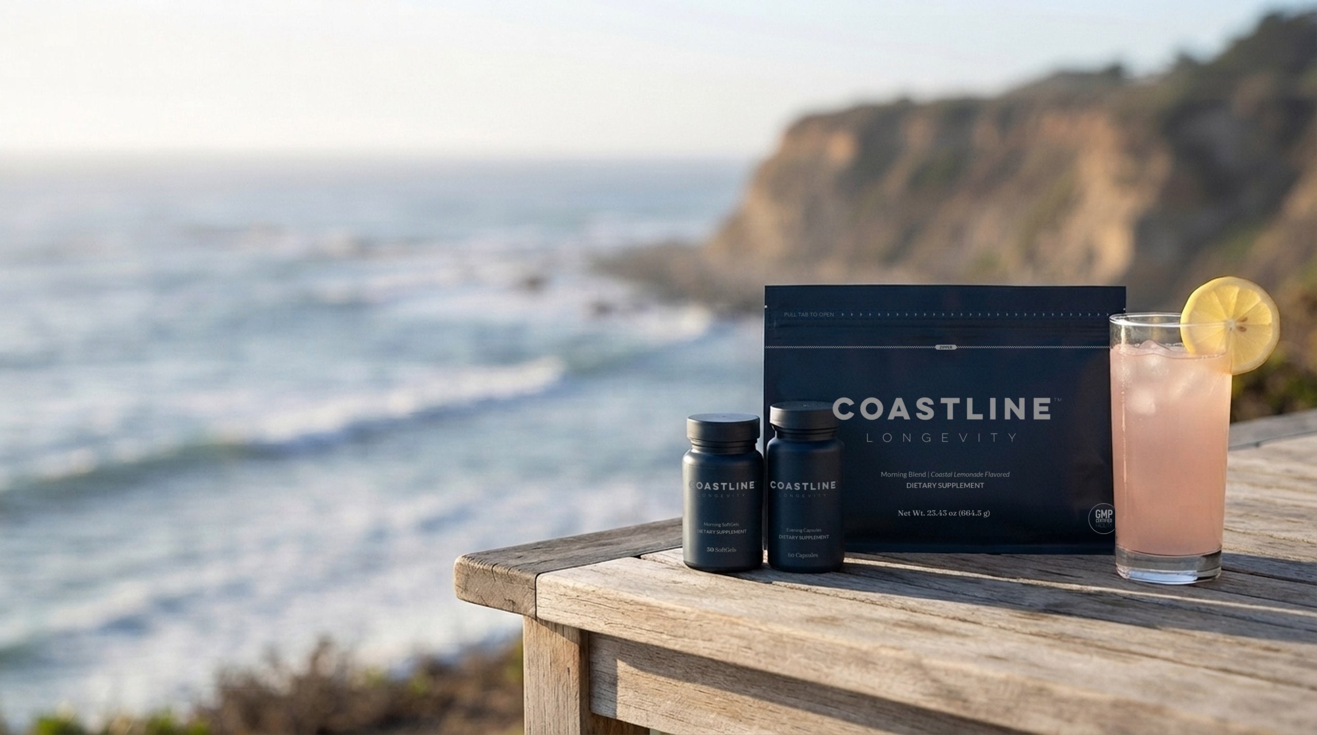 Coastline Morning Blend, Morning SoftGels and Evening Capsules with a glass of Coastal Lemonade on a clifftop table by the ocean