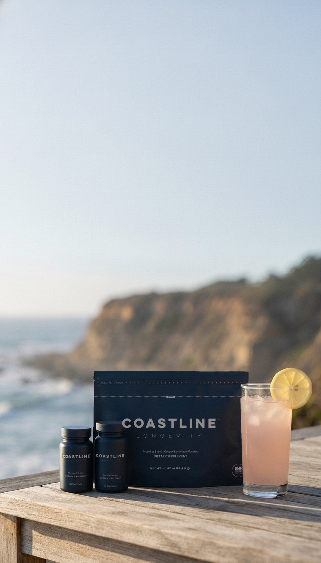 Coastline Morning Blend, Morning SoftGels and Evening Capsules with a glass of Coastal Lemonade on a clifftop table by the ocean